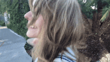 a woman 's hair is blowing in the wind while walking down a sidewalk