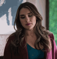 a woman wearing a blue top and a pink jacket