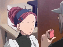 a woman with a blue headband is looking at a man holding a pink object