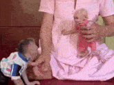 a woman in a pink dress is holding two small babies