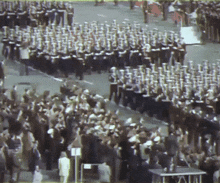 a large band marching down a street in front of a crowd of people