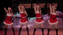 a group of women in santa costumes are dancing in front of a winter talent show sign