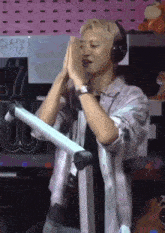 a man wearing headphones and a watch stands in front of a sign that says ' nct '