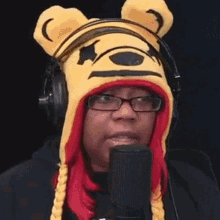 a woman is wearing a winnie the pooh hat and headphones while talking into a microphone .