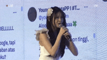 a woman is singing into a microphone in front of a screen that says app # 1