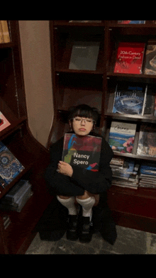 a woman sitting in a bookstore holding a book titled nancy spare