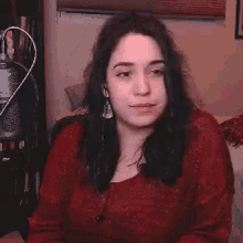a woman in a red sweater is standing in front of a microphone .