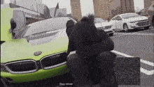 a man sits in front of a green bmw with the words they never on the bottom