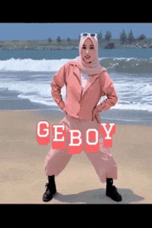 a woman in a hijab is standing on a beach with the word geboy written on the bottom