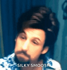 a man with a beard is making a funny face while looking at himself in the mirror .