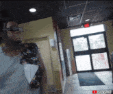 a man standing in a hallway with a red exit sign on the ceiling
