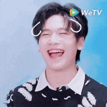 a young man is smiling with a wetv logo on his head