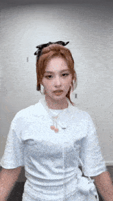 a woman wearing a white t-shirt and a necklace is standing in a room .