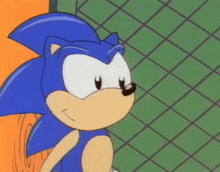 sonic the hedgehog is giving a peace sign in front of a chain link fence .