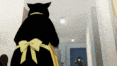 a black cat with a yellow bow on it 's back