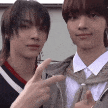 two young boys are standing next to each other and one is pointing at the camera