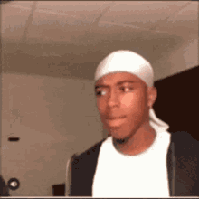 a man wearing a white headband and a black jacket is making a funny face .