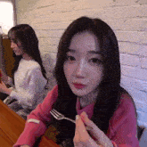 a girl in a pink sweater holds a fork in her hand
