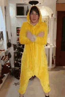 a man in a yellow costume is standing in front of a christmas tree