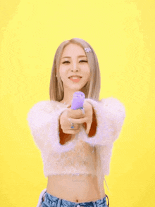 a woman in a white crop top is holding a purple object in her hands while confetti is falling around her .