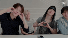 a group of young men are making a heart shape with their hands while sitting at a table