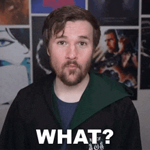 a man with a beard is wearing a green hooded jacket and says what