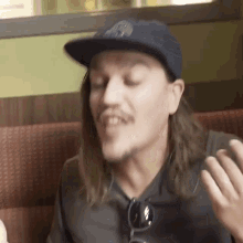 a man with long hair wearing a hat and sunglasses is talking