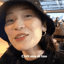 a woman wearing a black hat and hoop earrings says " chet mie di tao " on the bottom