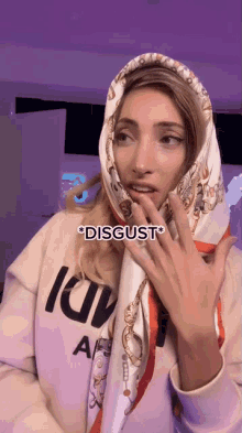 a woman wearing a scarf and a louis vuitton sweatshirt says disgust on her face