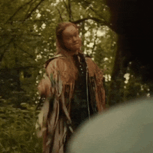 a woman in a native american outfit stands in the woods