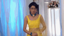 a woman in a yellow dress is standing in front of a window in a room .