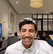 a man wearing headphones and a white shirt smiles for the camera