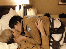 two men are kissing on a bed and one of them has a patch on his chest that says ' a ' on it