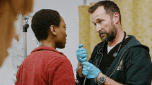 a doctor is talking to a patient in an emergency room while holding a syringe .