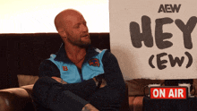 a man sitting in front of a sign that says hey ew