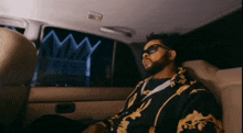 a man sitting in the back seat of a car with a crown in the background