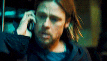 a man with long hair is talking on a cell phone