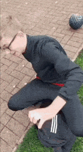 a young boy is kneeling down on the sidewalk holding a backpack .