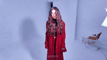 a woman in a red coat is standing in a room with the name njfaerie on the bottom right