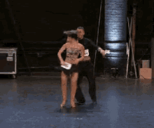 a man and a woman are dancing on a stage and the man has a number 55 on his shirt
