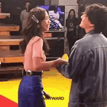 a man and a woman are standing next to each other holding hands and smiling .