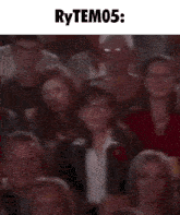 a blurry picture of a crowd of people sitting in a theater with the words rytem05 written above them .