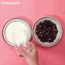 a person is holding a glass in front of plates of milk and chocolate