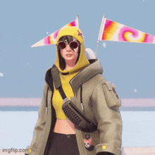 a woman wearing a yellow hoodie and sunglasses is standing on a beach .