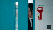 a woman in a suit and tie is peeking out from behind a door .