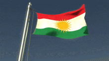 a red white and green kurdish flag is flying in the wind