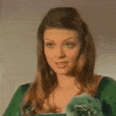 the woman is wearing a green dress and giving a thumbs up .