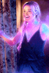 a woman with purple hair and a black dress is smiling