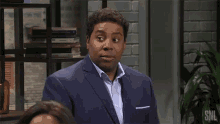 a man in a suit is standing in front of a snl plant