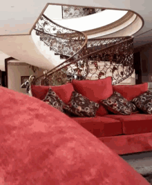 a red couch sits in front of a spiral staircase in a living room